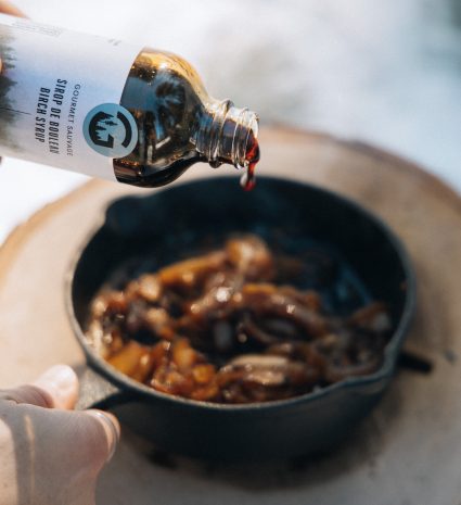 Flacon de sirop versant dans une poêle en fonte