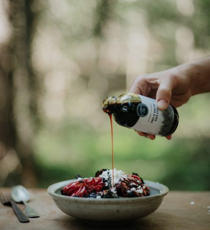 Bouteille de sirop versant sur un plat de fruits rouges et fromage