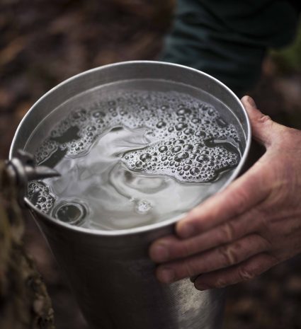 Seau en métal rempli d'eau dans un environnement forestier