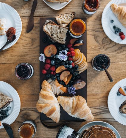 Viennoiseries, petits fruits et confitures sur une table en bois