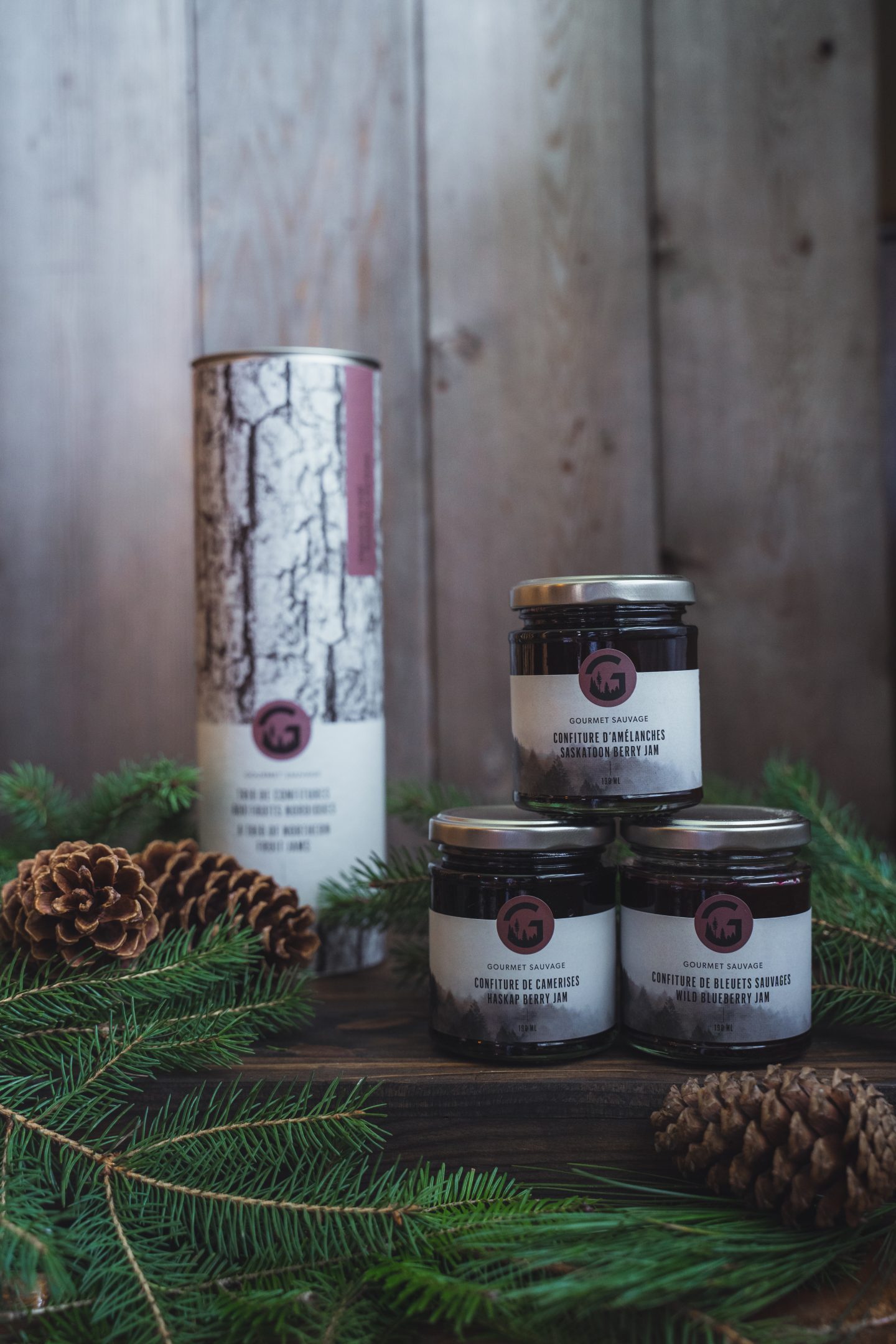 pots de confiture sur une surface en bois avec des branches de sapin