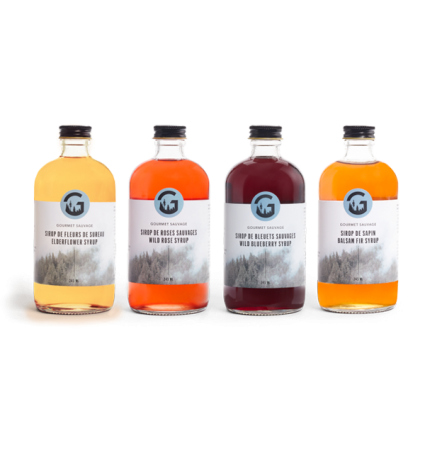 Quatre bouteilles de sirop de sureau, rose, bleuets et sapin alignées