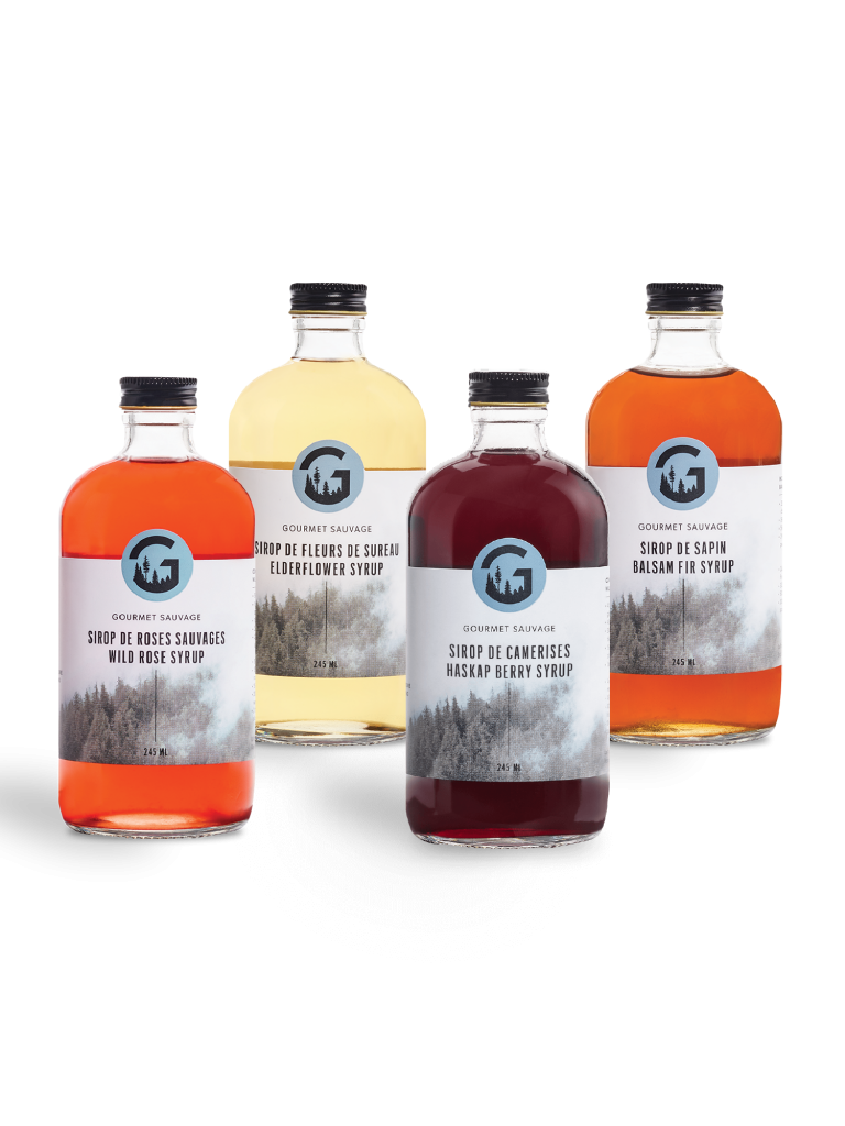 Quatre sirops forestiers en bouteilles de verre aux couleurs variées