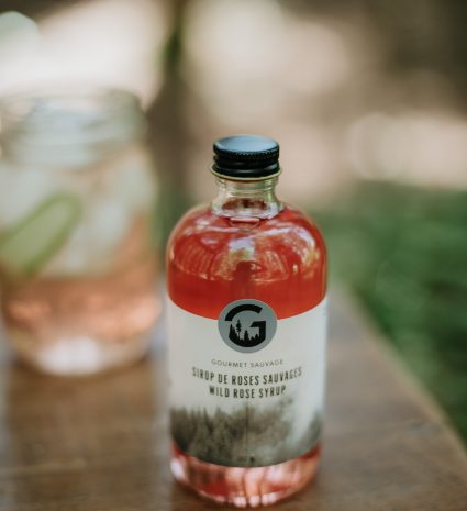 Bouteille de sirop de roses sauvages de Kamouraska sur une table en bois