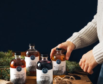 Bouteilles de sirop de camerises sur une table avec des branches de conifères