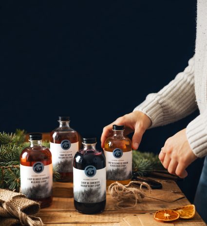 Bouteilles de sirop de camerises sur une table avec des branches de conifères
