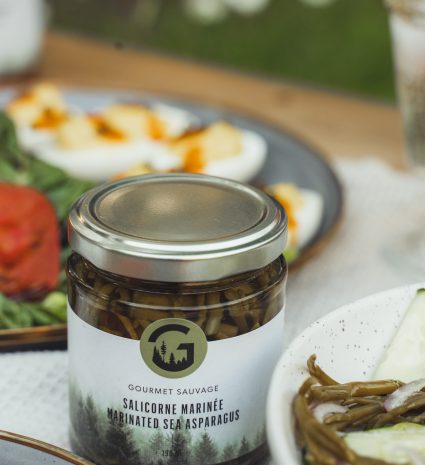 Pot de salicorne marinée sur une table dressée avec des assiettes