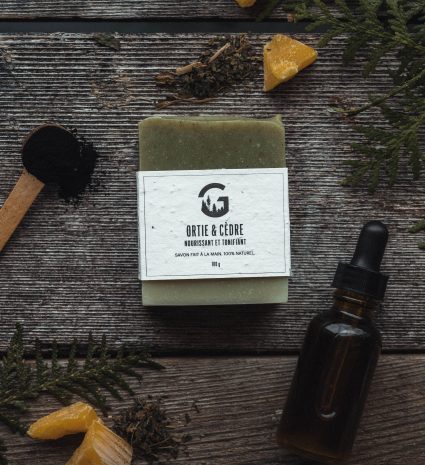 Savon ortie et cèdre sur des planches de bois avec des plantes
