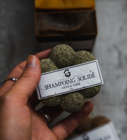 Shampooing solide ortie-prêle tenu dans une main