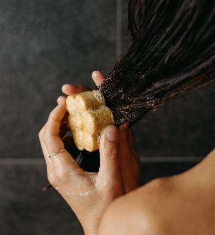Pain de shampooing solide à l’argousier tenu contre des cheveux mouillés