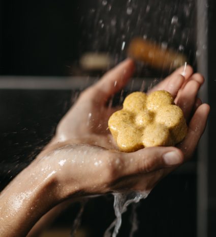 Pain de shampooing solide dans des mains sous l’eau