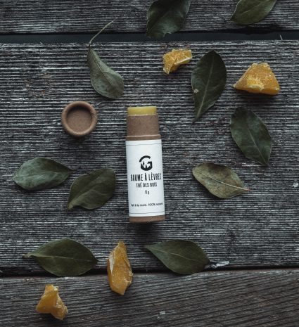 Baume à lèvres au thé des bois sur une planche avec des feuilles