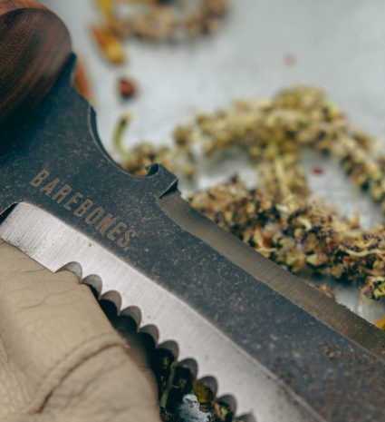 Couteau hori hori sur surface métallique avec débris de plantes