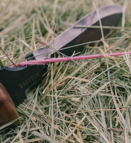 Couteau hori hori à manche de bois dans l’herbe sèche