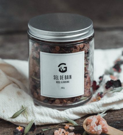 Pot de sel de bain rose et avoine sur un linge et une table en bois