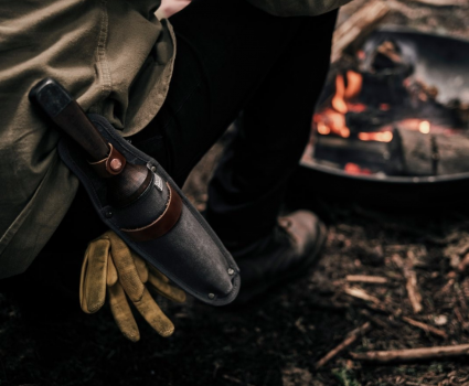 Outil de coupe fixé à la ceinture d'une personne près d'un feu de camp