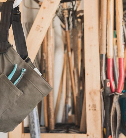 Sac de récolte en toile suspendu parmi des outils de jardin