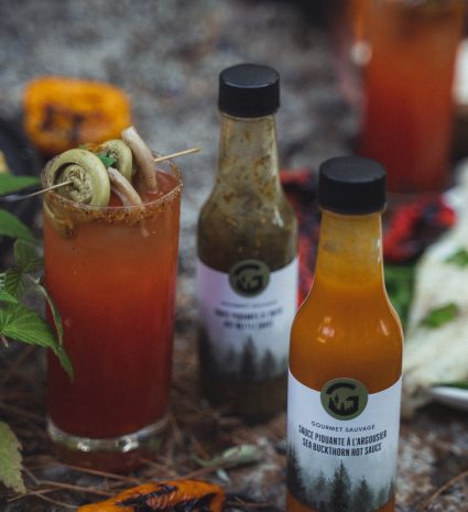 Bouteille de sauce piquante à l’argousier près d’un verre garni