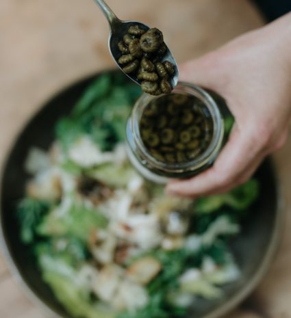 Câpres de boutons de marguerites dans une cuillère au-dessus d’une salade