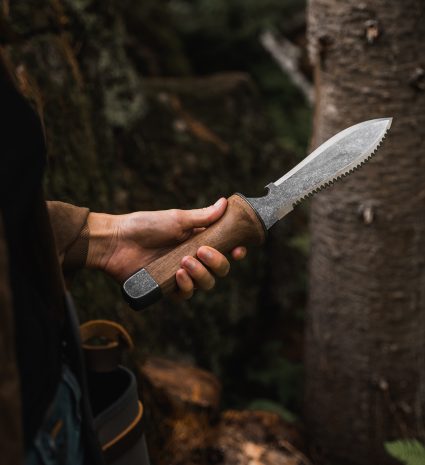 Couteau hori hori tenu à la main dans une forêt