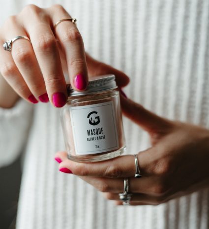 Pot de masque bleuet et rose tenu entre deux mains
