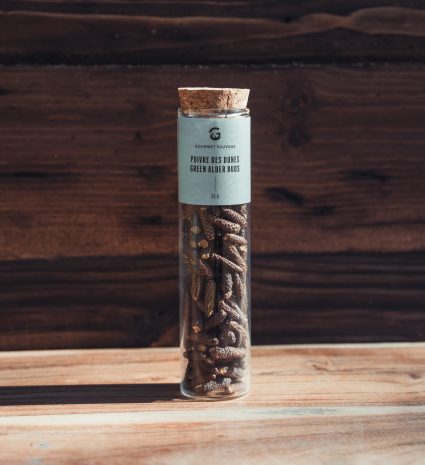 Poivre des dunes en tube de verre posé sur une table en bois