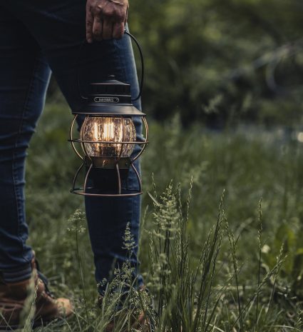 Lanterne rechargeable tenue à la main dans un sous-bois
