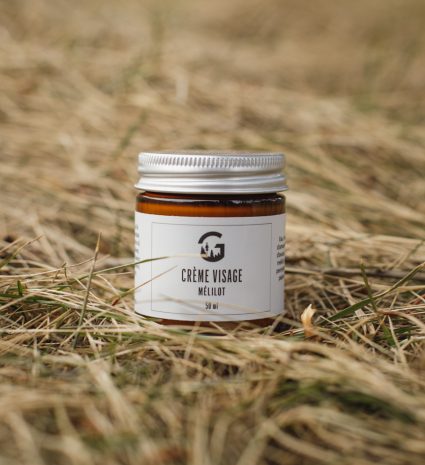 Crème visage au mélilot dans un pot posé sur de l'herbe sèche