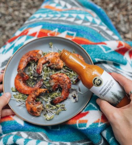 Sauce piquante à l’argousier tenue au-dessus d’une assiette de crevettes