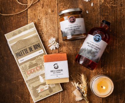 Pot de canneberges confites, bouteille de sirop, savon à la verveine sur table en bois