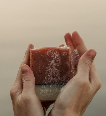 Savon airelle-lavande tenu entre des mains couvertes de mousse