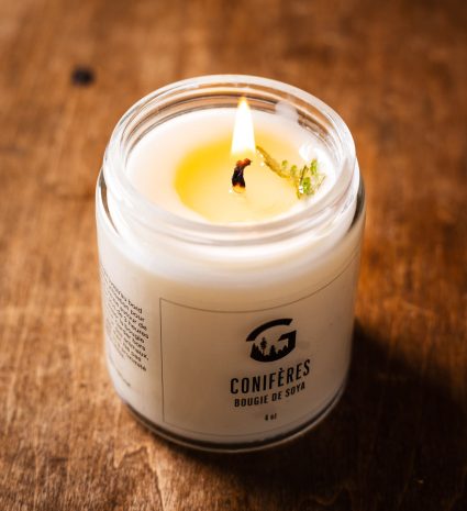 Chandelle aux conifères allumée dans un pot de verre sur une table en bois