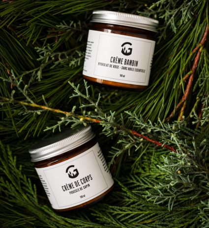 Pots de crème de corps et crème bambin dans des branches de sapin