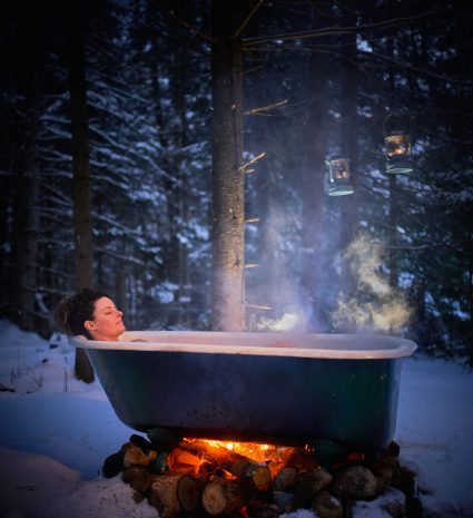 Personne dans une baignoire chauffée au feu en forêt enneigée