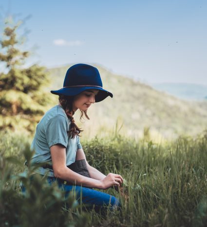 Personne assise dans les herbes hautes avec des collines en arrière-plan
