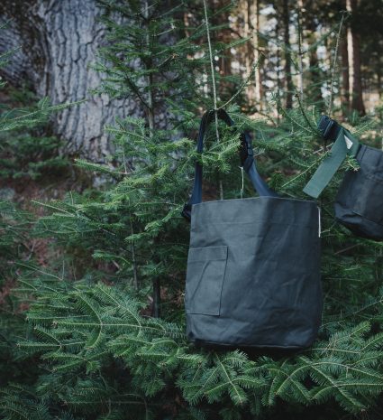 Sacs de récolte suspendus parmi des branches de conifères