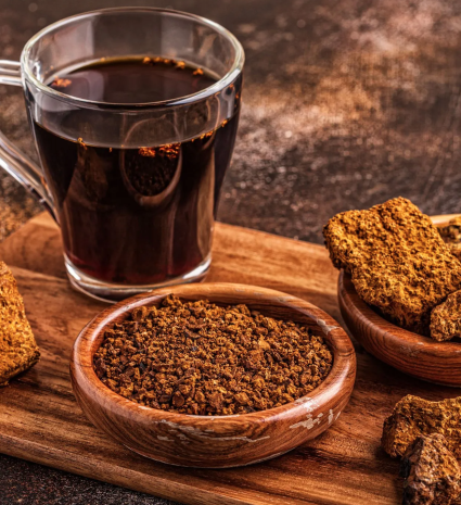 Pépites de chaga dans un bol en bois avec une tasse de boisson foncée