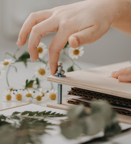 Presse à fleurs en bois serrée à la main près de petites fleurs