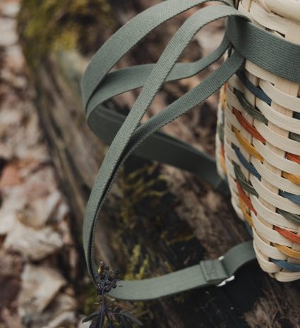 Sac-à-dos de cueillette tressé avec ses sangles sur une souche en forêt