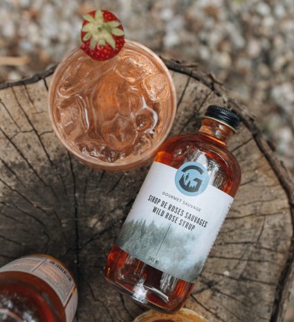 Bouteille de sirop de roses sauvages de Kamouraska sur une souche
