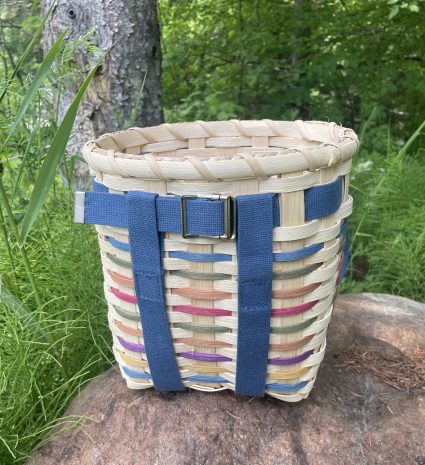 Sac-à-dos de cueillette en panier tressé posé sur un rocher en forêt