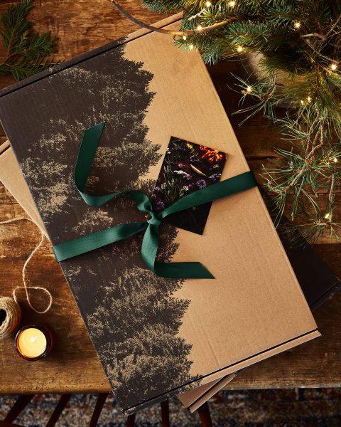coffret gourmand en carton avec illustration de conifères et ruban vert