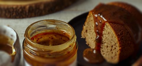 Pot de gelée brune à côté d'une tranche de gâteau sur assiette noire