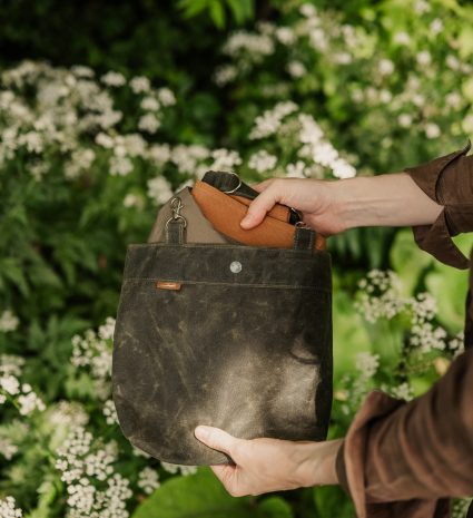Tablier de cueillette tenu devant des plantes à fleurs blanches