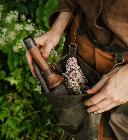 Tablier de cueillette avec fleurs et outil en forêt