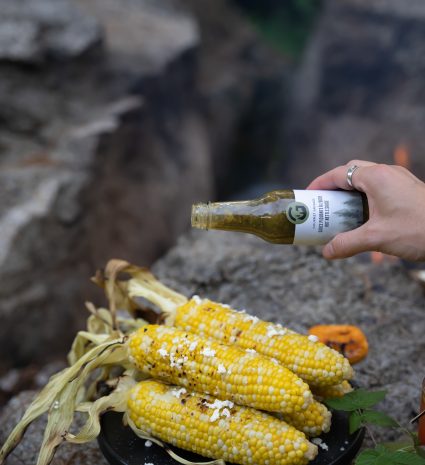 Épis de maïs sur une poêle noire avec une bouteille de sauce