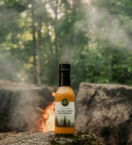 Bouteille de sauce piquante à l’argousier sur un rocher moussu