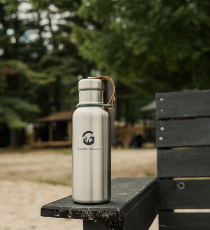 Gourde isotherme en métal posée sur l’accoudoir d’un banc