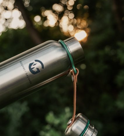Gourde isotherme avec bouchon attaché, devant des arbres en forêt
