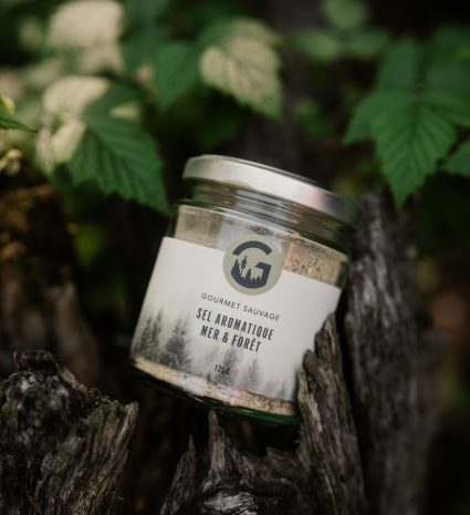 Pot de sel aromatique mer et forêt posé sur une souche